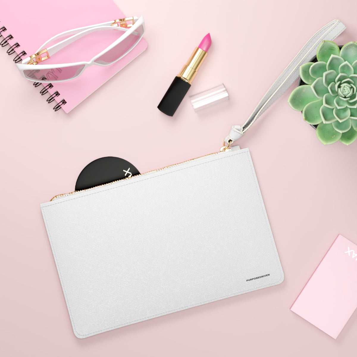 PurposeDriven™ minimalist white wristlet clutch styled with everyday essentials on soft pink background