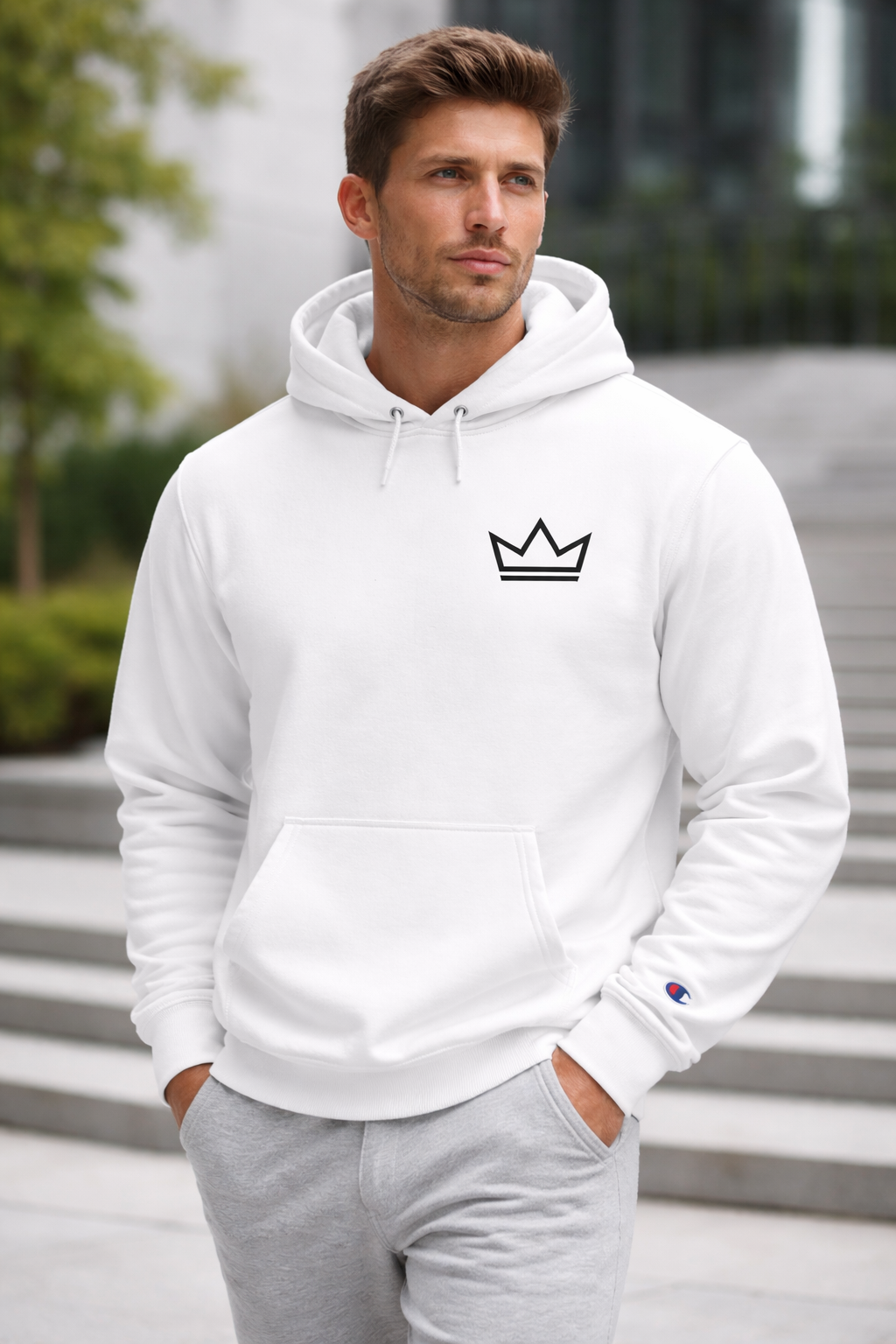 Male model wearing the white Ascension Hoodie by PurposeDriven, featuring a minimalist crown logo in an outdoor lifestyle setting.