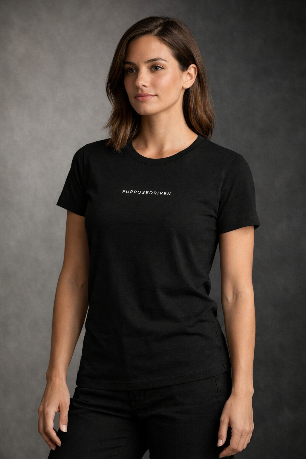 Female model wearing black PurposeDriven minimalist t-shirt, premium motivational streetwear on dark studio background